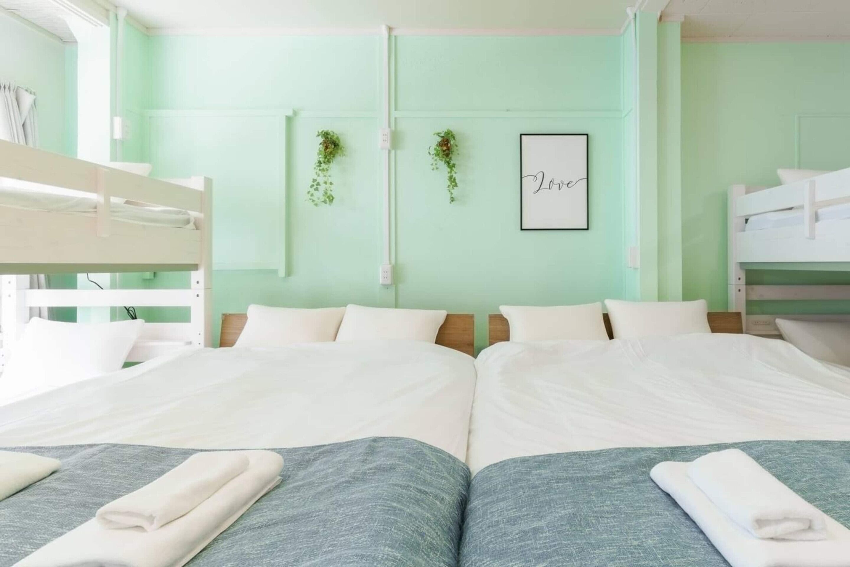 A twin room with two beds, a green wall, and a framed 'Love' sign.