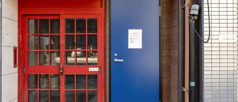 A red door with glass panels and a blue door with a sign.
