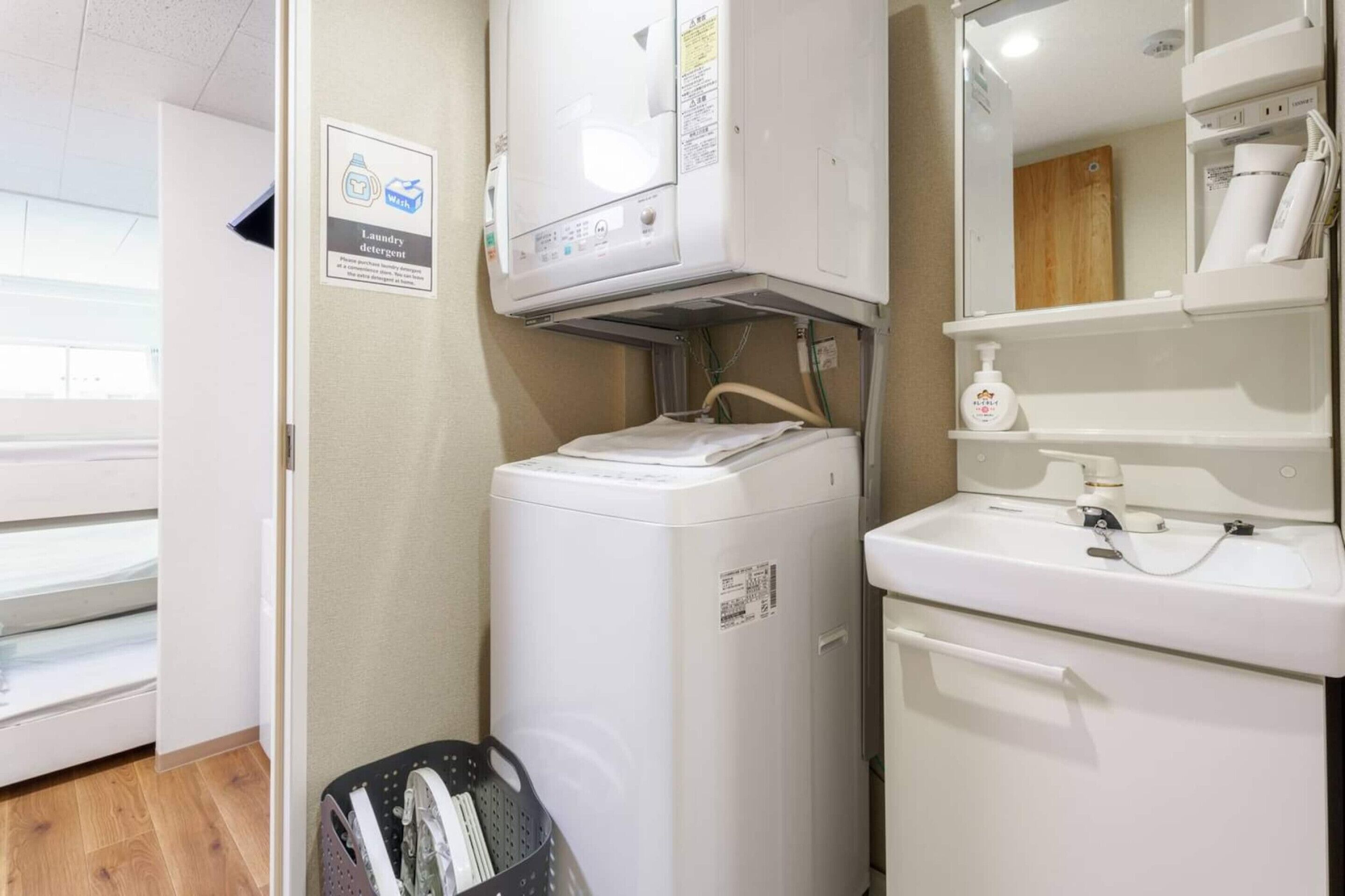A compact laundry area with a washing machine, a sink, and a mirror.