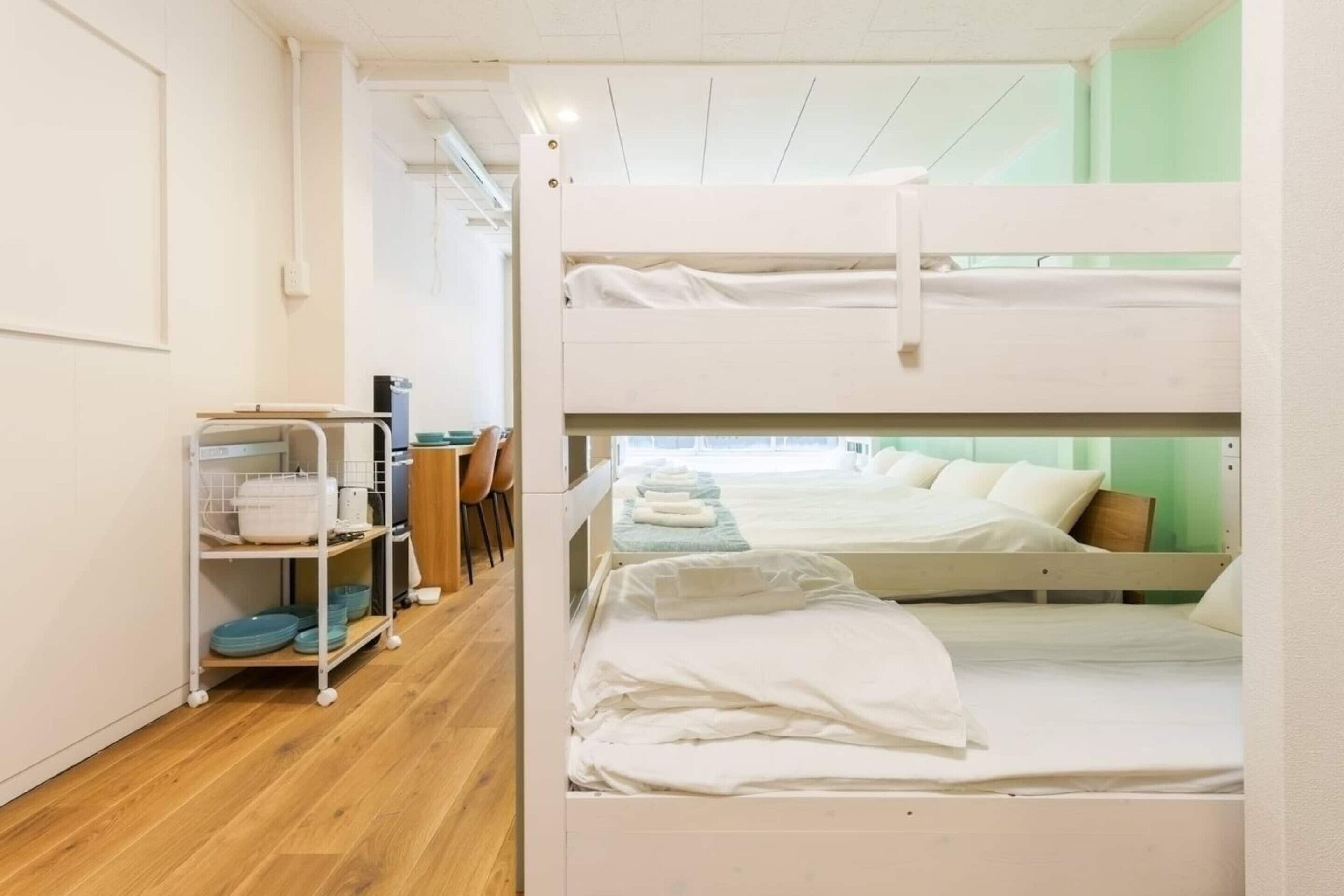 Une chambre avec un lit superposé, un bureau et une chaise, une étagère avec de la vaisselle et une fenêtre avec vue.