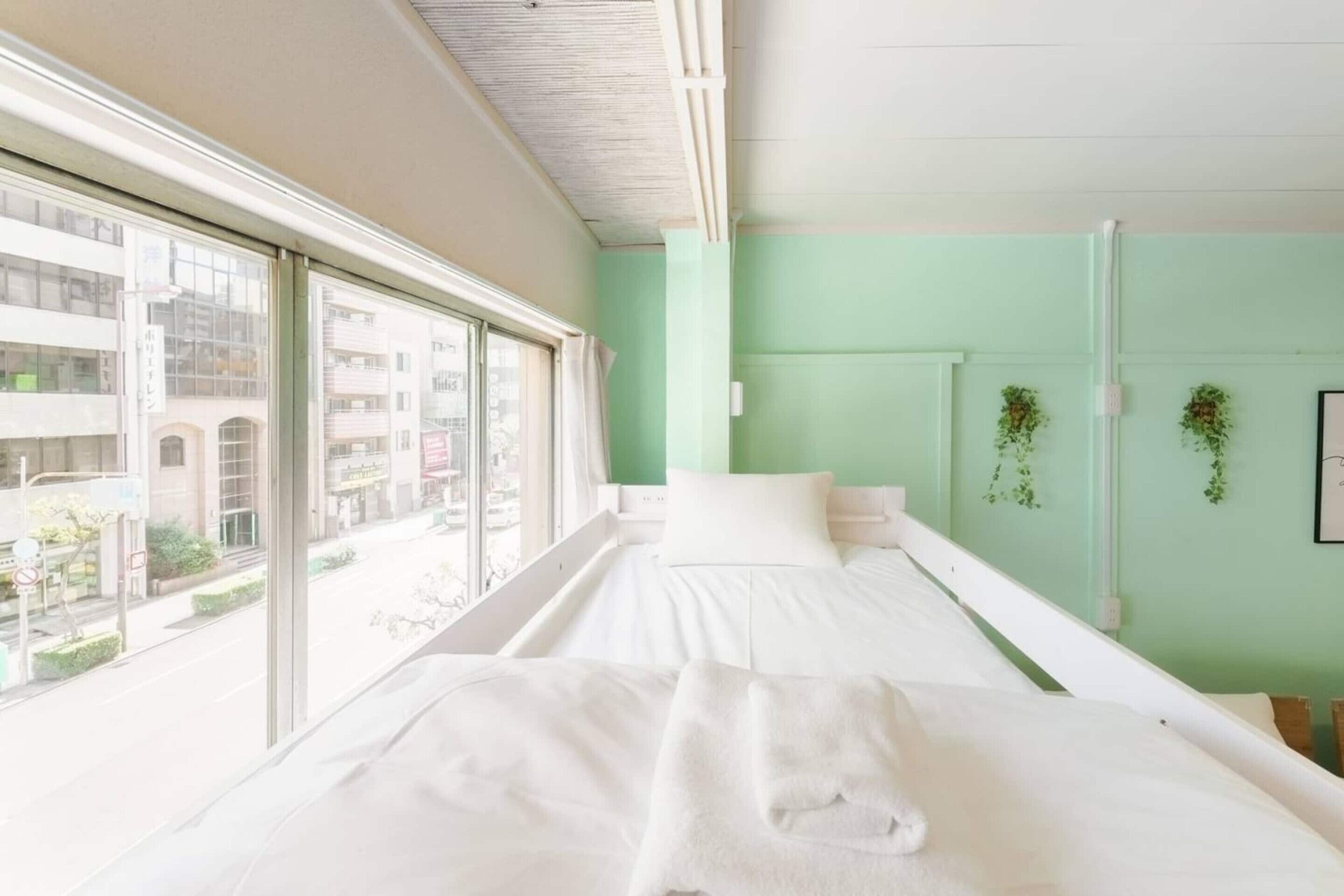 Ein Hotelzimmer mit zwei Betten, großen Fenstern und Blick auf die Stadt.