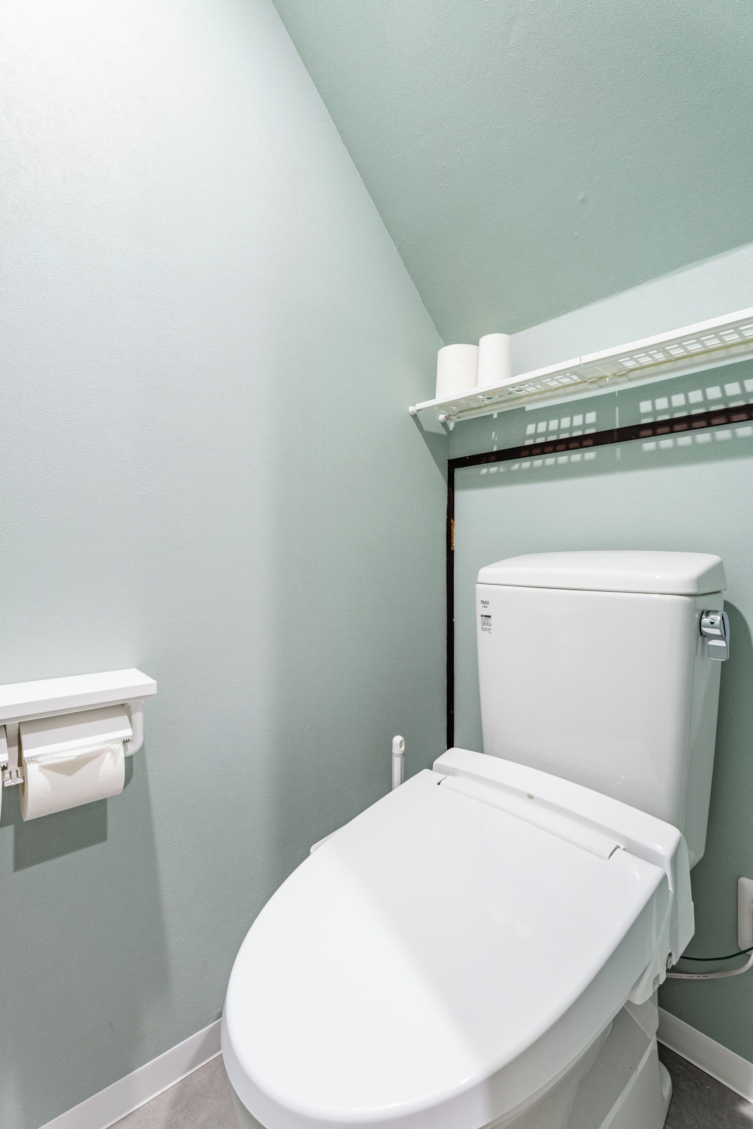 Een badkamer met een wit toilet, een toiletpapierhouder en een plank met toiletpapier.