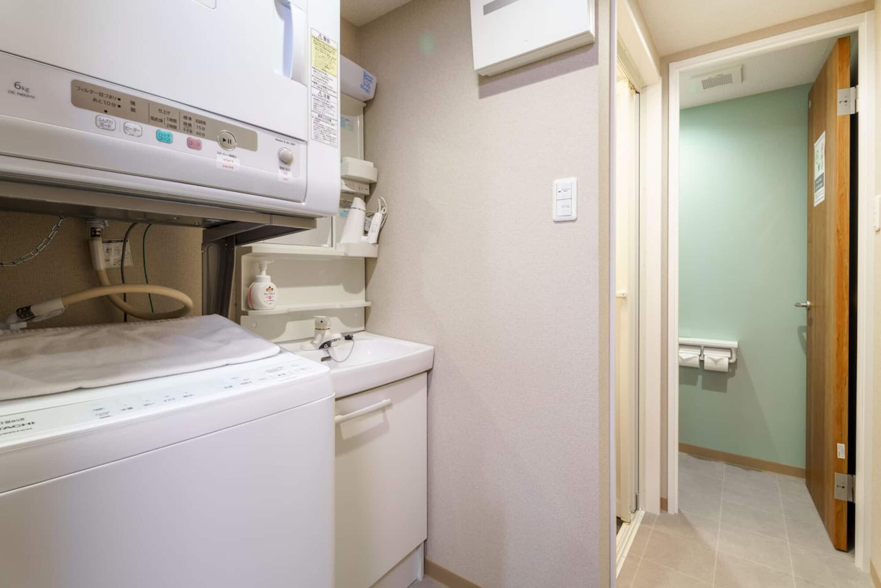 A laundry area with a washing machine, a sink, and a shelf with toiletries.