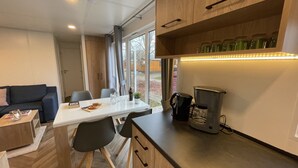 Une cuisine moderne avec des meubles en bois, une machine à café et un coin repas comprenant une table et des chaises.