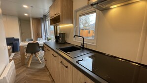 Une cuisine moderne avec des meubles en bois, un plan de travail noir et une fenêtre donnant sur un quartier résidentiel.