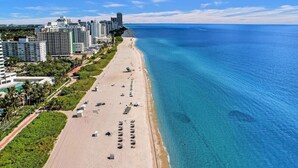A coastal cityscape with a long sandy beach, high-rise buildings, and clear blue waters. - Cute Ocean View Condo Beach Service 1217 (Miami Beach)