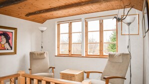 A cozy room with wooden beams, a large window, two chairs, a lamp, and a framed picture on the wall. - 2 bedroom nice home in Fjälkinge (Fjälkinge)