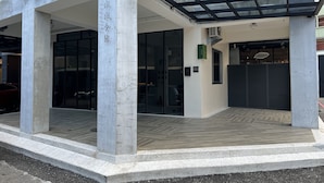 Un edificio moderno con vestíbulo cubierto, puertas de vidrio amplias y suelo de baldosas.