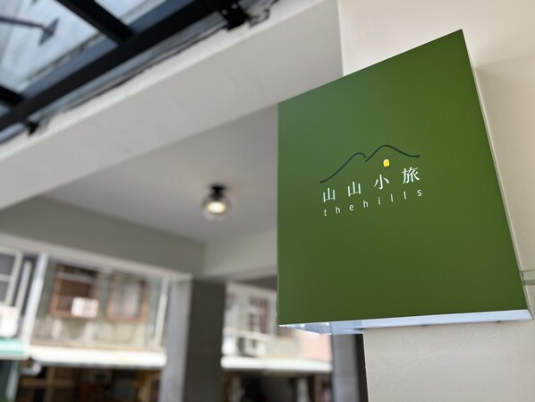 Un cartel verde con texto blanco y un gráfico de una montaña, colocado en una pared dentro de un edificio de diseño moderno.