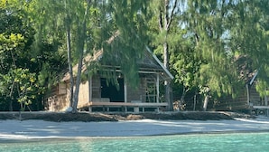 A beachfront property with a wooden structure, clear turquoise water, and surrounding trees. - Wai Resort - Raja Ampat  (Jerief Island)