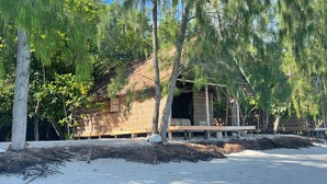 A rustic wooden structure with a thatched roof, surrounded by trees and a sandy ground. - Wai Resort - Raja Ampat  (Jerief Island)