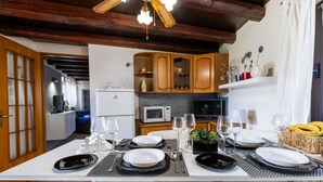 A modern kitchen with wooden cabinets, a built-in microwave, and a dining area set for six with white plates and black placemats. - Da Norma by Interhome (Terzo d'Aquileia)