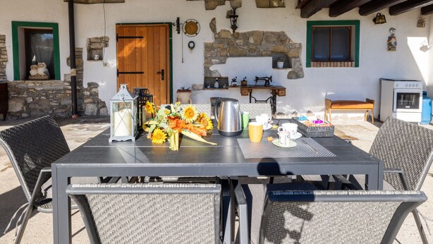 An outdoor dining area with a table set for two, surrounded by wicker chairs. - Da Norma by Interhome (Terzo d'Aquileia)