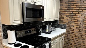A kitchen with white cabinets, a black stove, and a microwave. - Home in Miami Gardens (Miami)