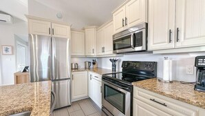 A kitchen with white cabinets, stainless steel appliances, granite countertops, and a tiled floor. - Home Away Villa: Ideal for Island Adventures (Stanley Bridge)