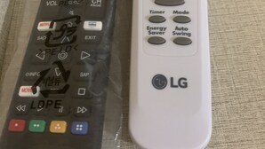 Two remote controls, one black and one white, on a textured surface.
