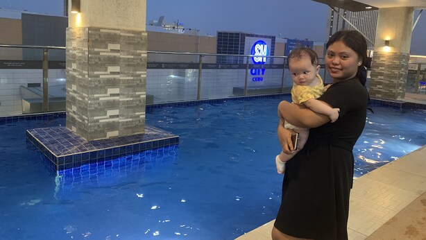 A pool area with a tiled edge, a glass barrier, and a sign with 'SUN CITY CEBU' visible in the background.