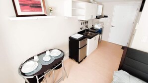 A compact kitchen with a dining area, a white door, and a framed picture on the wall.