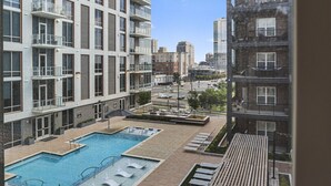 A modern apartment building with a rooftop pool area, including a swimming pool and sun loungers.