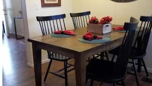 A dining area with a wooden table and black chairs, framed artwork on the wall, and a coffee mug sign. - River House (Parker)