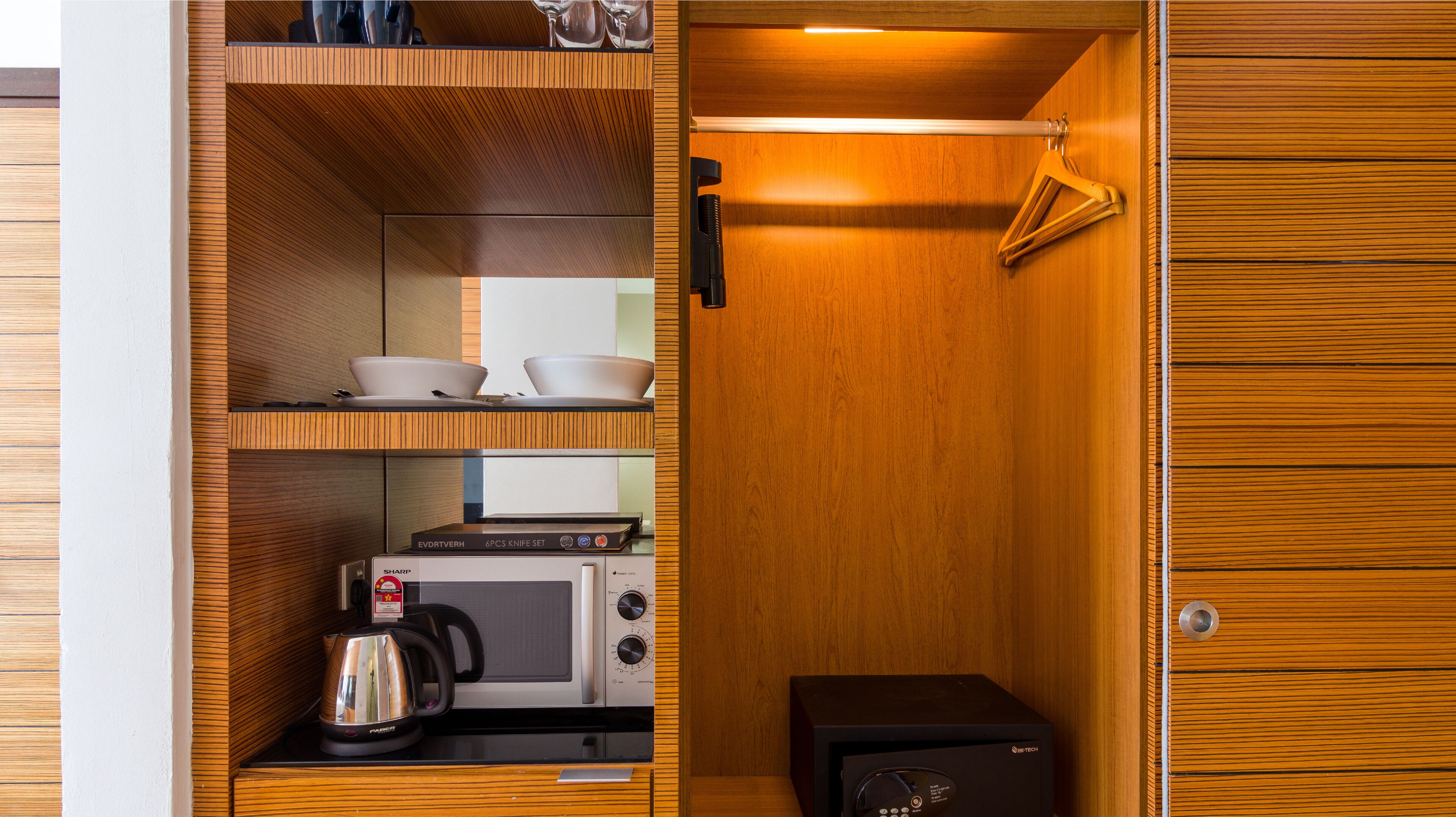 A compact kitchen with a microwave, kettle, and a small cabinet.