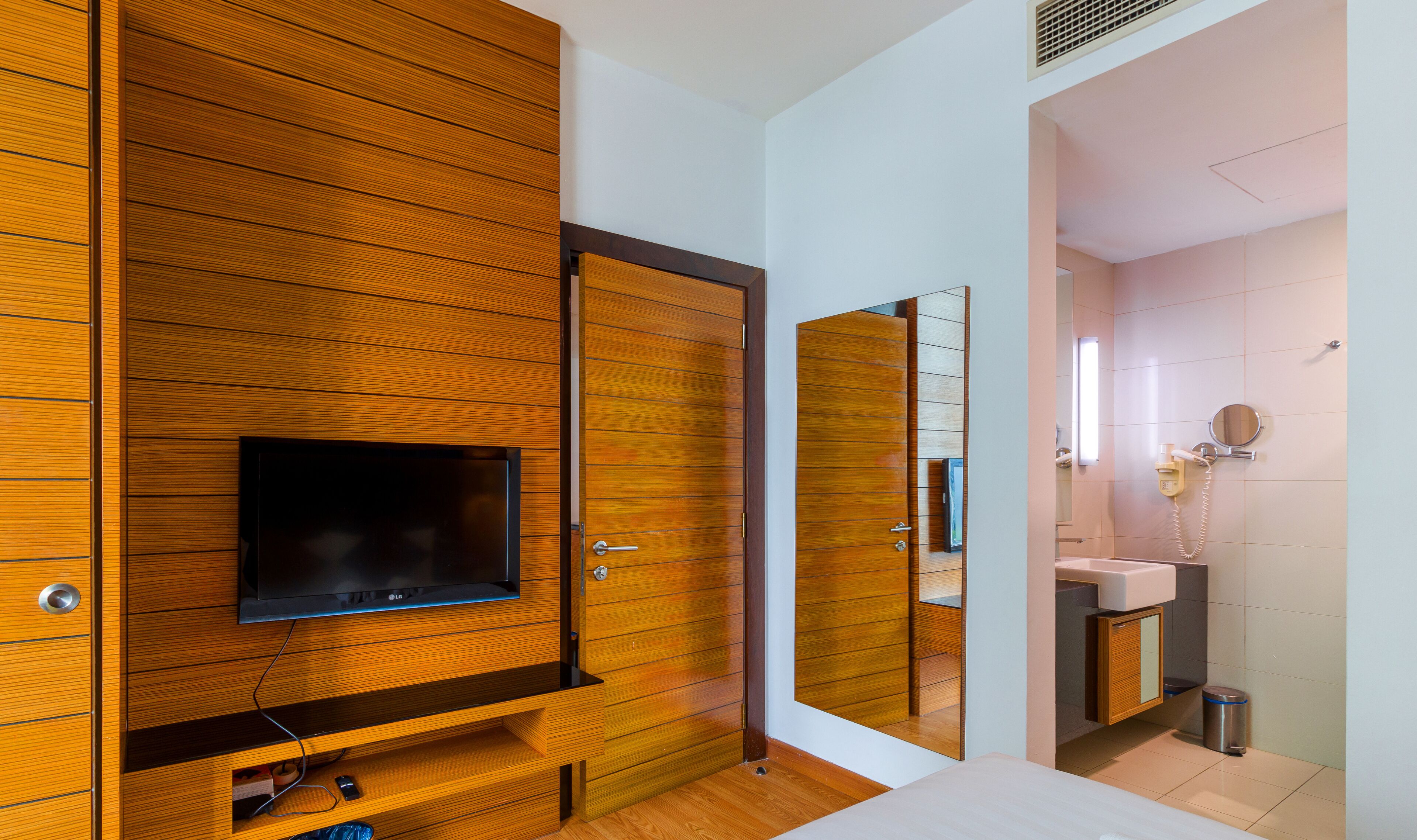 A modern bathroom with a wooden vanity, a mirror, and a toilet.