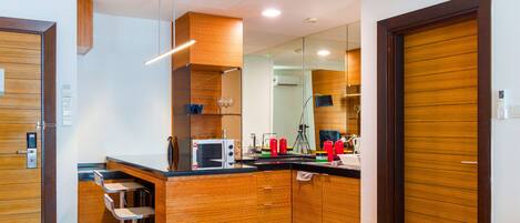 Una cocina moderna con muebles de madera, microondas integrado y una barra con taburetes.