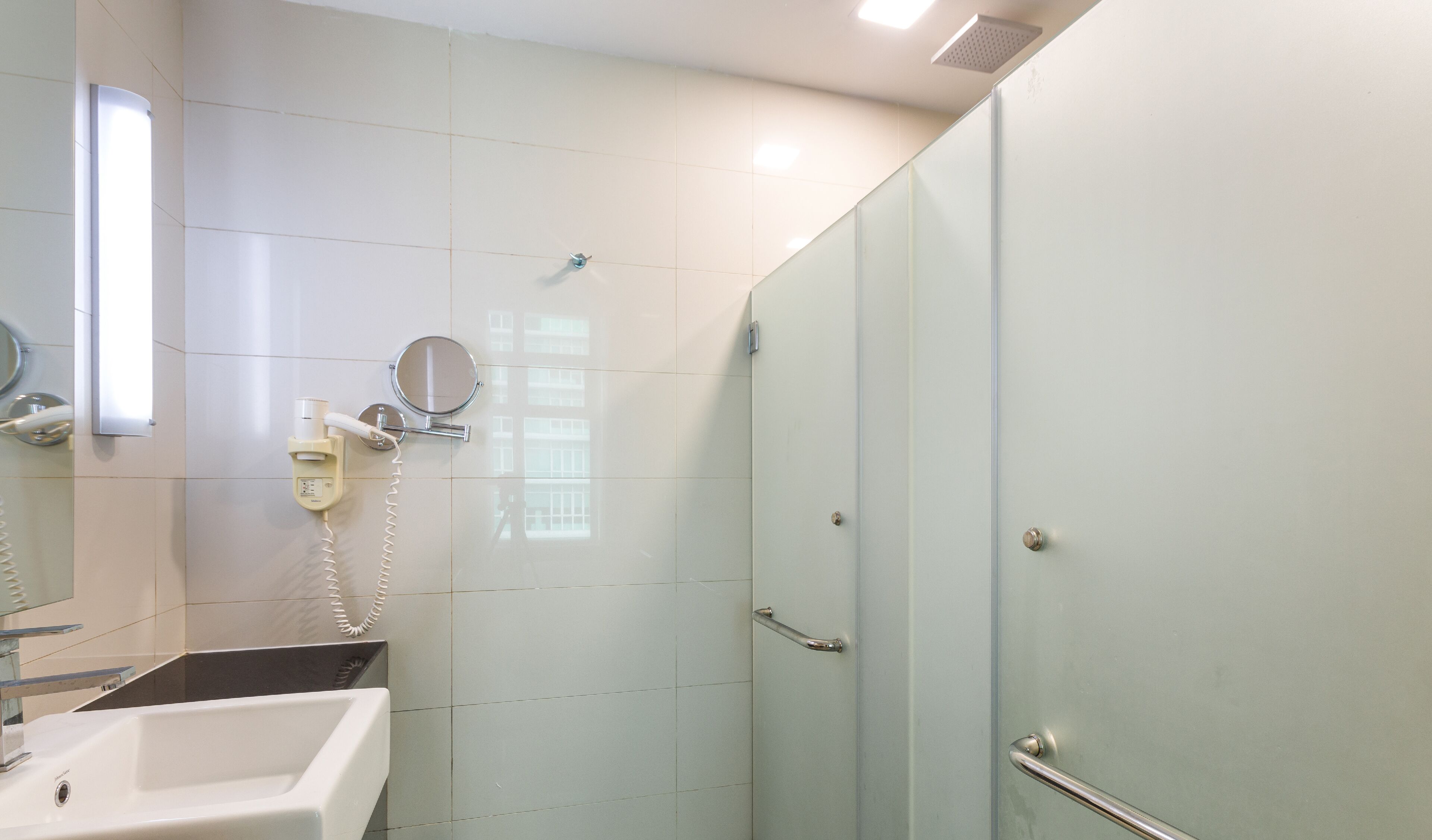 Een moderne badkamer met een douchecabine van glas, een wastafel en een spiegel.