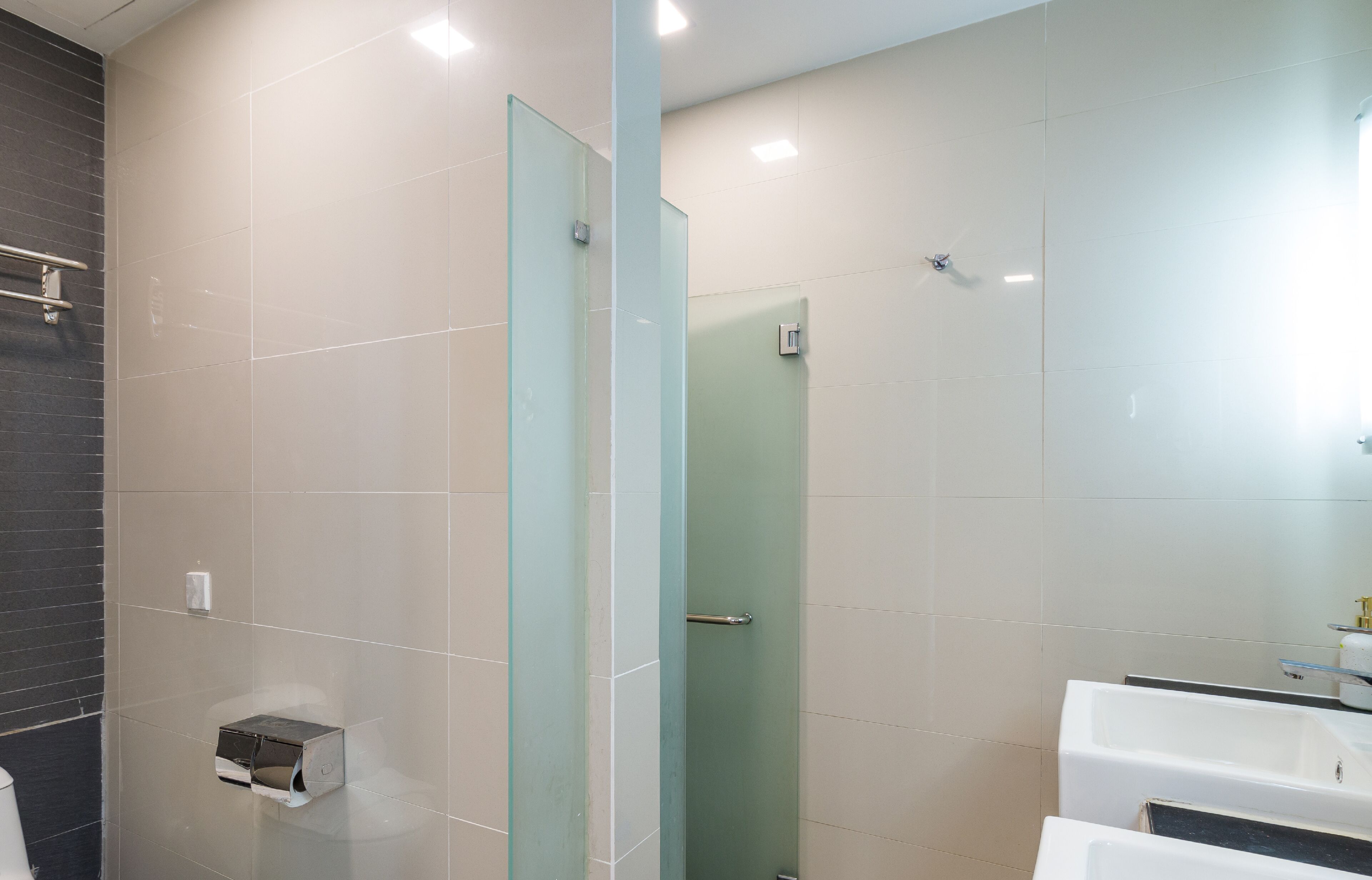 Uma casa de banho moderna com cabine de duche em vidro, lavatório branco e espelho.
