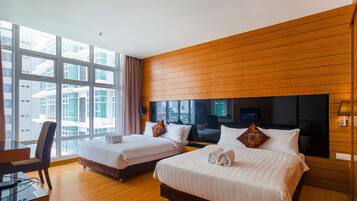 A hotel room with two beds, a desk, and a large window offering a city view.