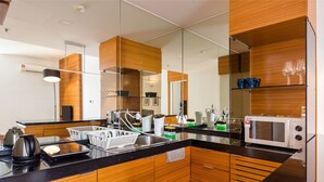 A modern kitchen with a black countertop, stainless steel appliances, and wooden cabinetry. - Dua Sentral KL Sentral (Kuala Lumpur)