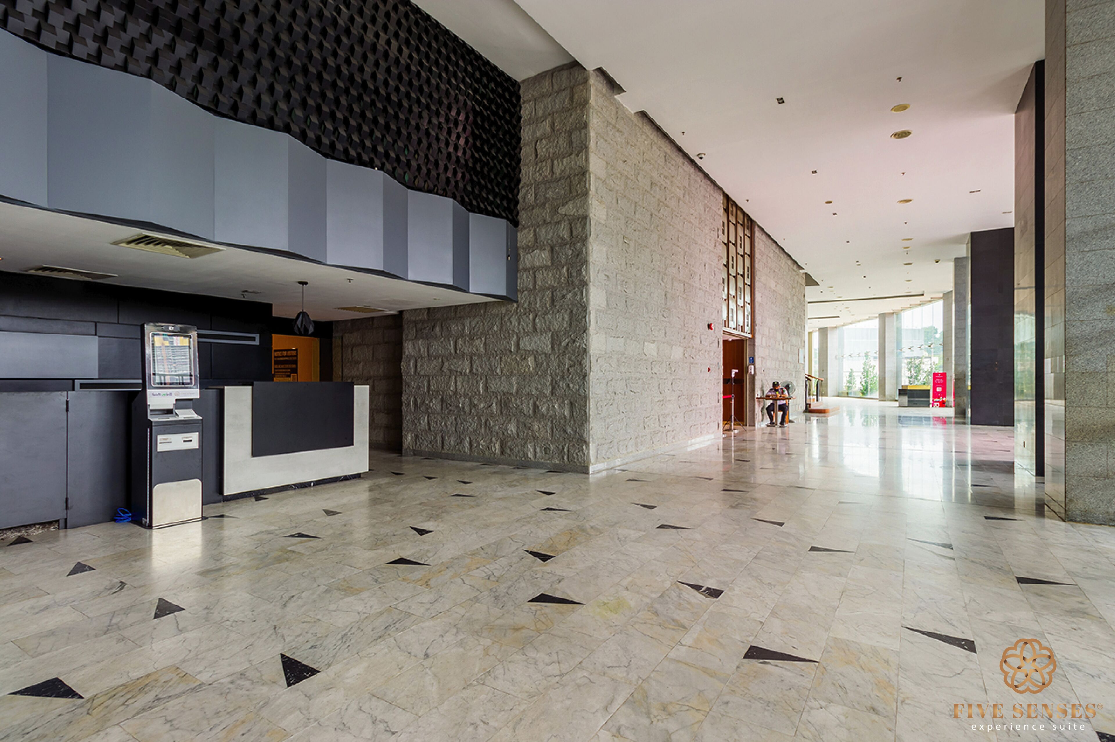 Un vestíbulo amplio con una recepción, una pared de piedra y un piso de baldosas.