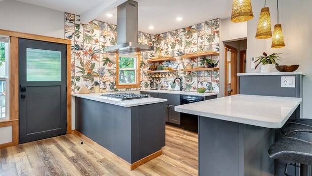 Een moderne keuken met een centraal eiland, houten planken en een spatwand met tropisch thema.
