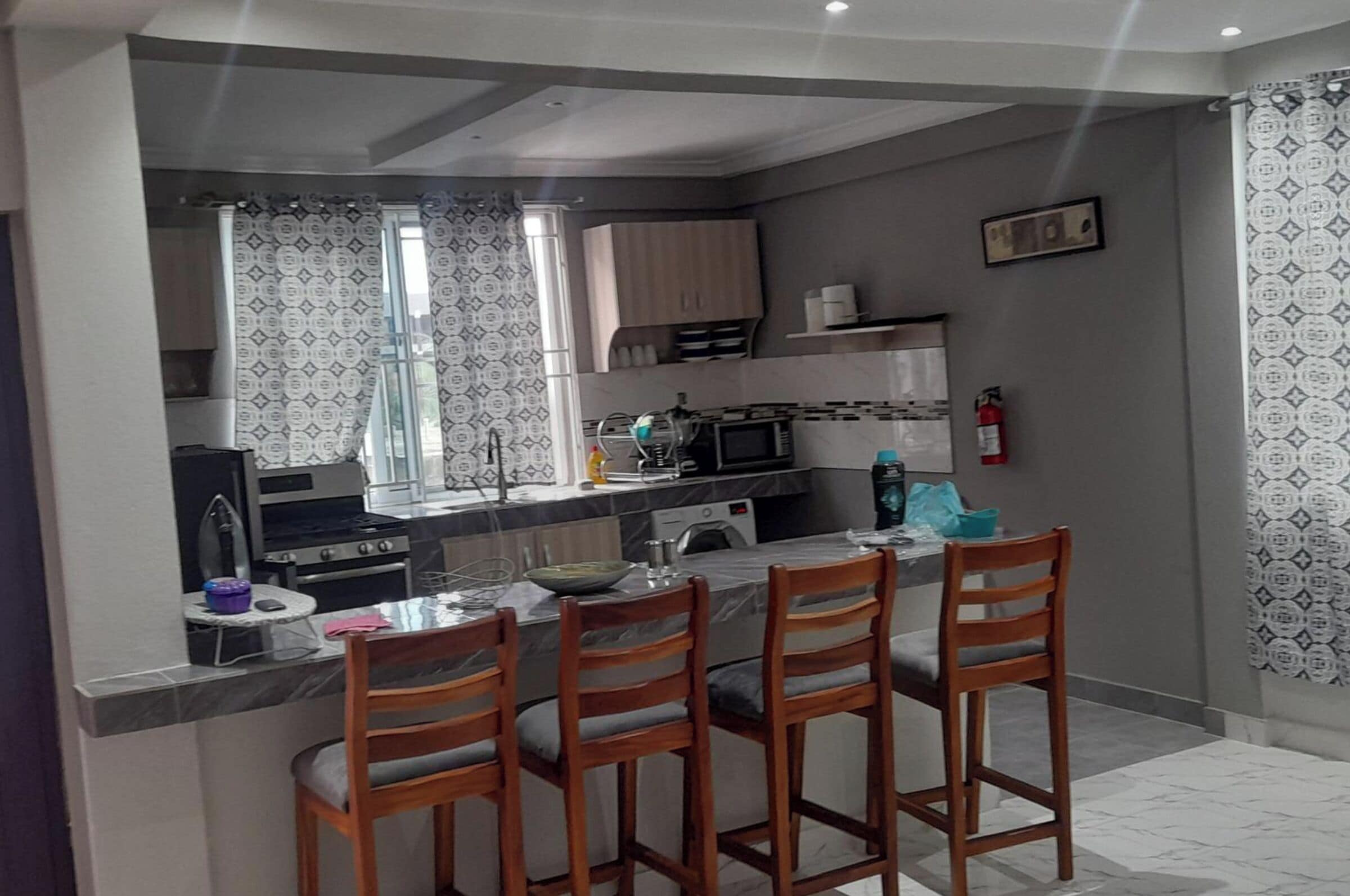 A compact kitchen with a dining area, featuring a microwave, stove, and a small island with bar stools.