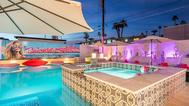 A swimming pool with a tiled deck, a hot tub, and a mural with the text "Blushica Sanctuary".