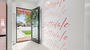 A modern interior with a glass door leading to an outdoor area, a wall with repeated text, and a clean, minimalist design.