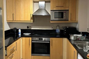A modern kitchen with wooden cabinets, a stainless steel range, a microwave, and a gas stove. - Captivating 1-Bed Apartment in London (London)