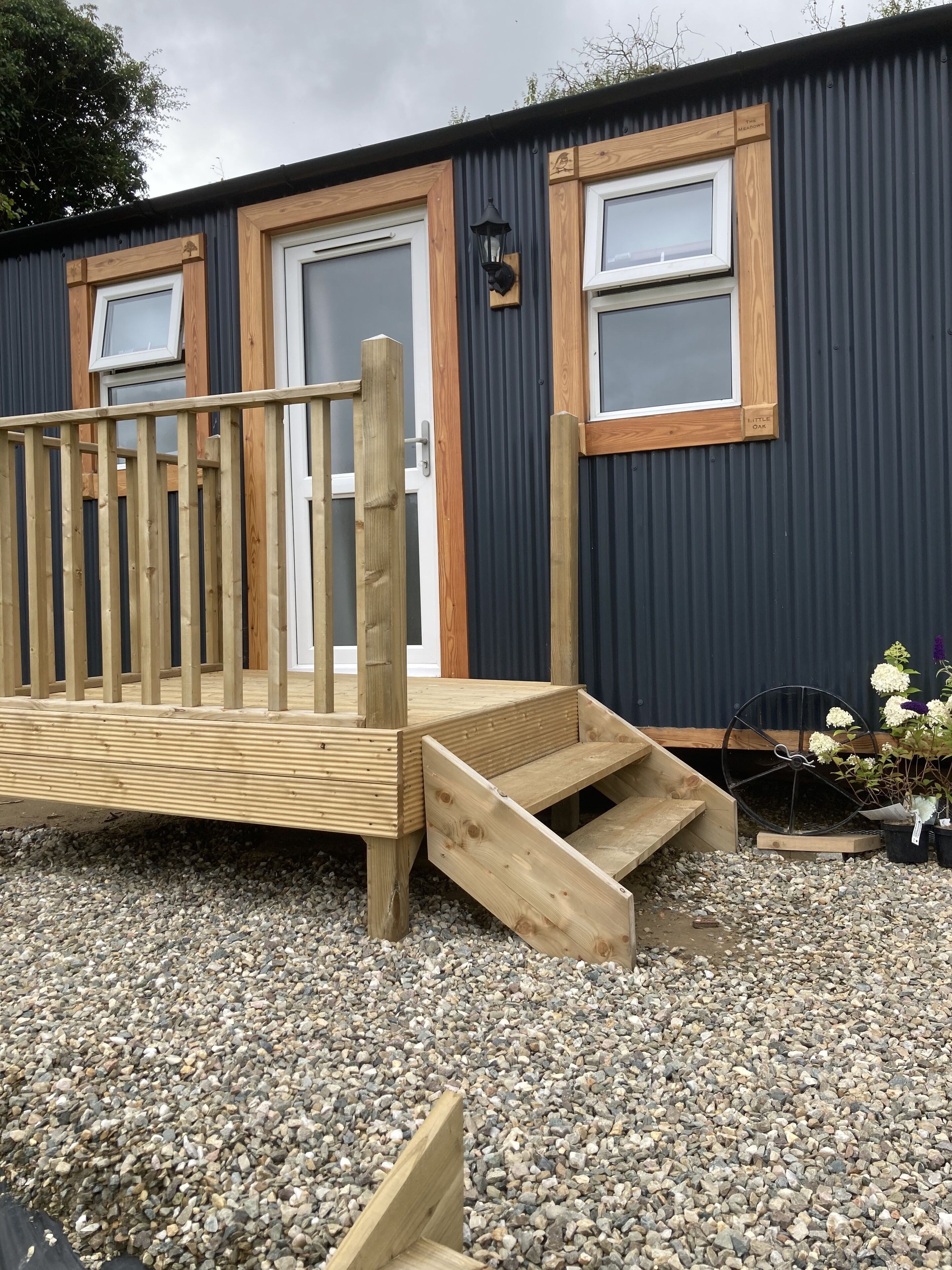 A wooden deck with a ramp leading to a door, surrounded by gravel.
