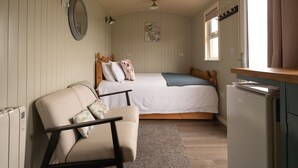 A small, cozy bedroom with a single bed, a chair, a small table, and a refrigerator. - 1 Bed Shepherds Hut-Sleeps 2-Pets-Parking-Mtn View (Omagh)