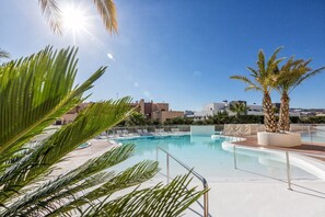 A swimming pool with a sunlit sky, palm trees, and modern buildings in the background. - Sara | Sea view - pool - terrace (La Cala de Mijas)