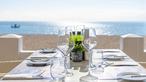A table set for dining with empty wine glasses and bottles, a small potted plant, and a view of the sea. - Sara | Sea view - pool - terrace (La Cala de Mijas)