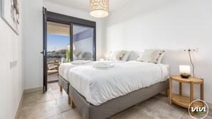 A bedroom with a bed, a bedside table with a lamp, a door leading to a balcony, and a view of the outside. - Sara | Sea view - pool - terrace (La Cala de Mijas)