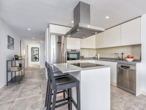 A modern kitchen with a central island, stainless steel appliances, and a minimalist design. - Sara | Sea view - pool - terrace (La Cala de Mijas)