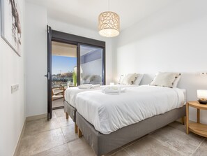 A bedroom with a bed, a bedside table with a lamp, a door leading to a balcony, and a view of the outside. - Sara | Sea view - pool - terrace (La Cala de Mijas)