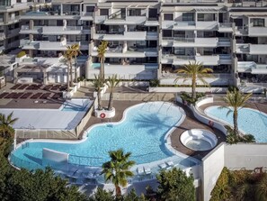 A modern hotel with multiple balconies, a central swimming pool, and palm trees. - Sara | Sea view - pool - terrace (La Cala de Mijas)
