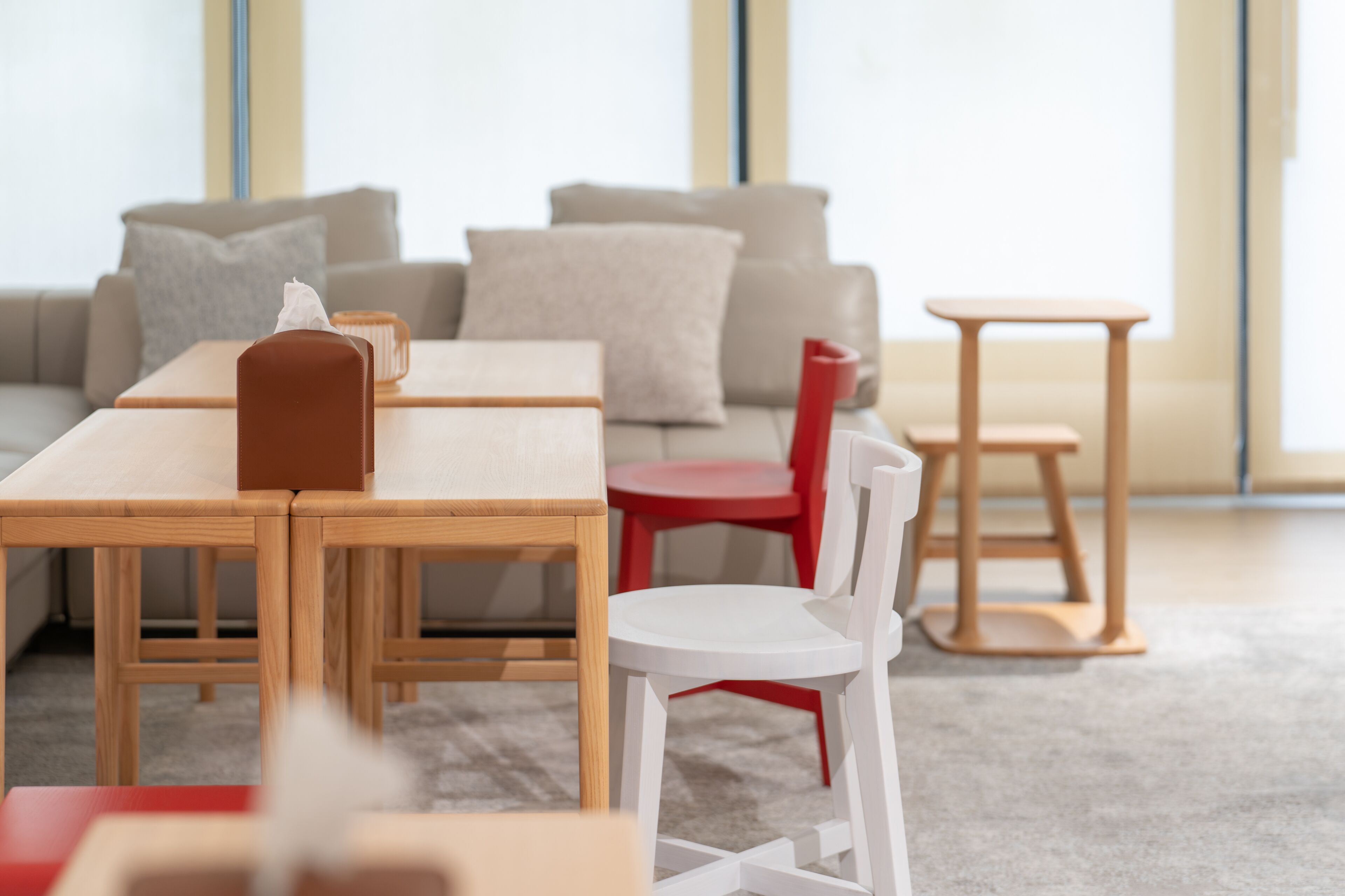 Una sala de estar moderna con una mesa de comedor de madera, una silla roja, una silla blanca y una pequeña mesita de madera.