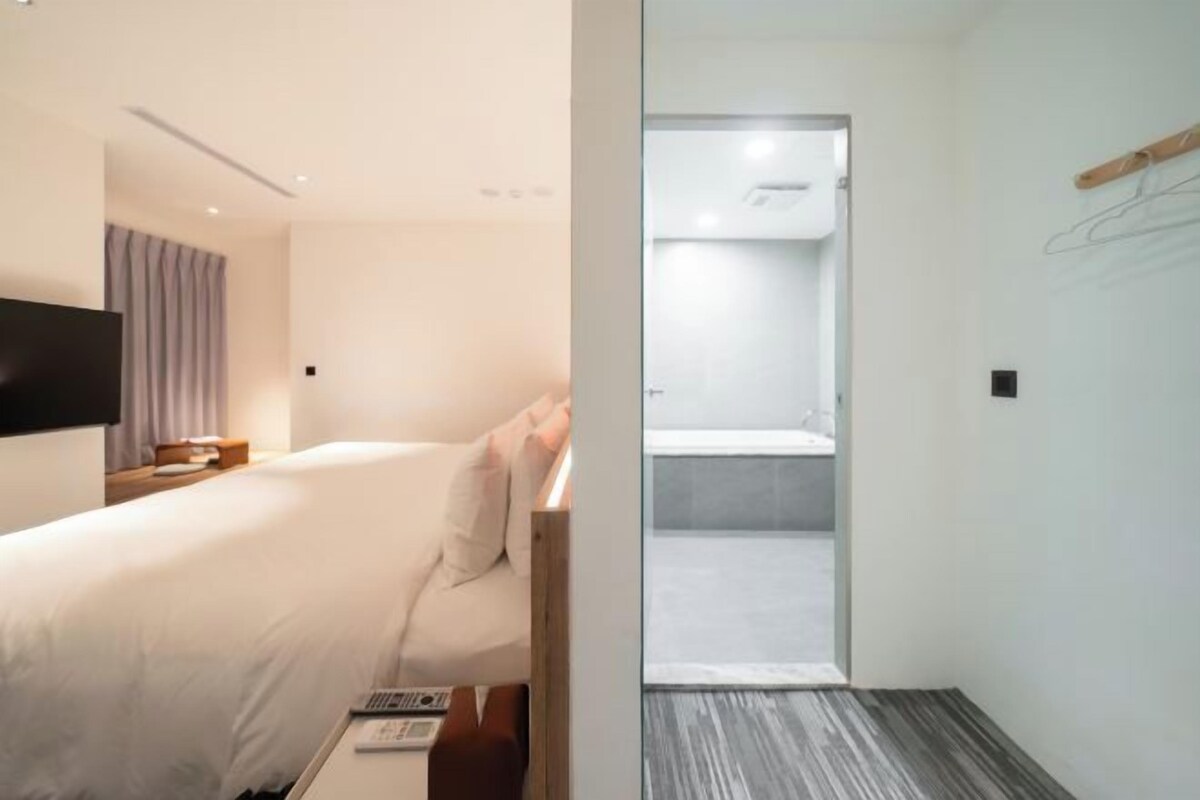 Una habitación de hotel moderna con una cama, mesita de noche y televisión.
