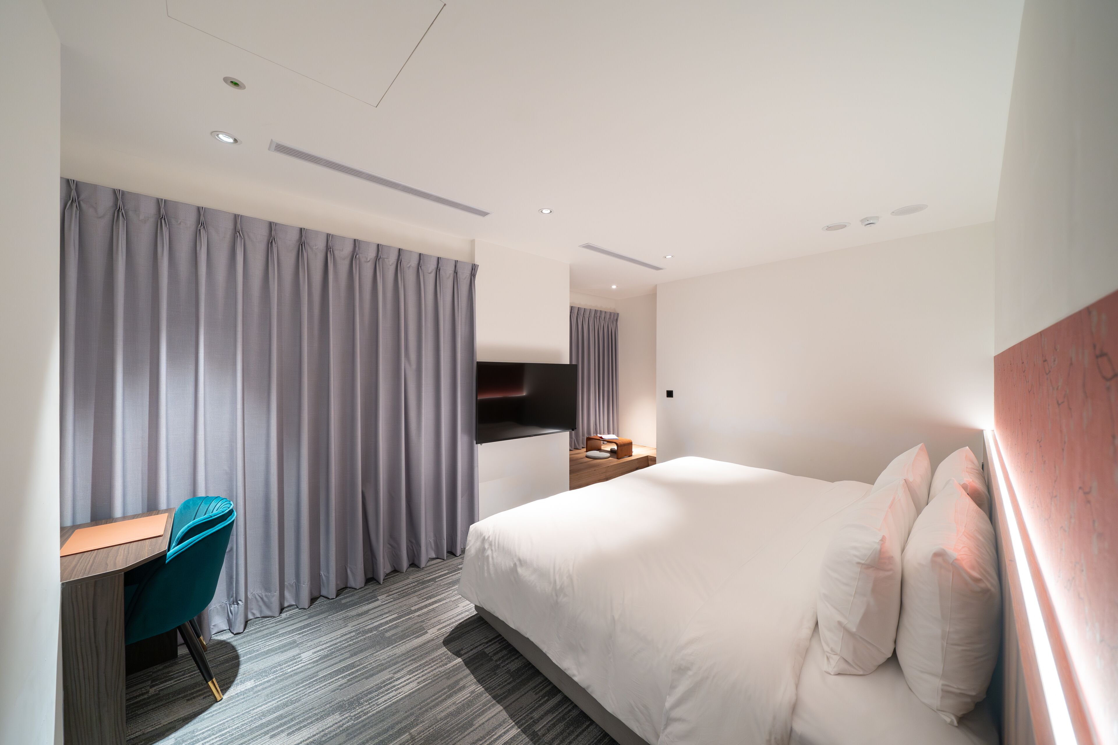 Una habitación de hotel moderna con una cama, un escritorio y una silla.