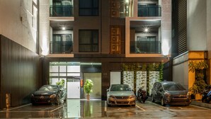 A multi-story building with balconies, a covered entrance, and a parking area with cars. - Kashotsu Bettei (Taichung)