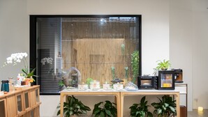 A modern living room with a wooden table, potted plants, a large window with bamboo blinds, and a coffee machine. - Kashotsu Bettei (Taichung)